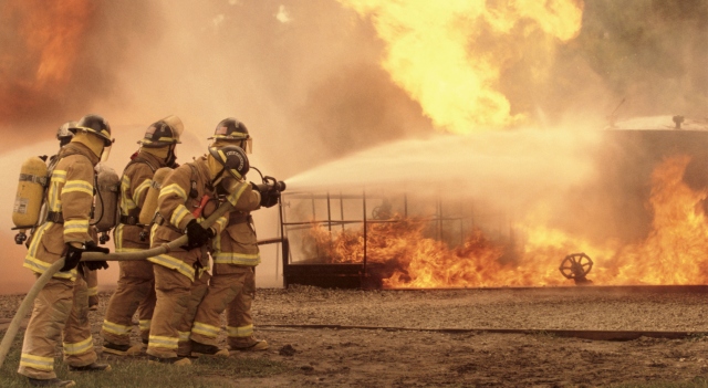 Firefighters aiming water hose at fire