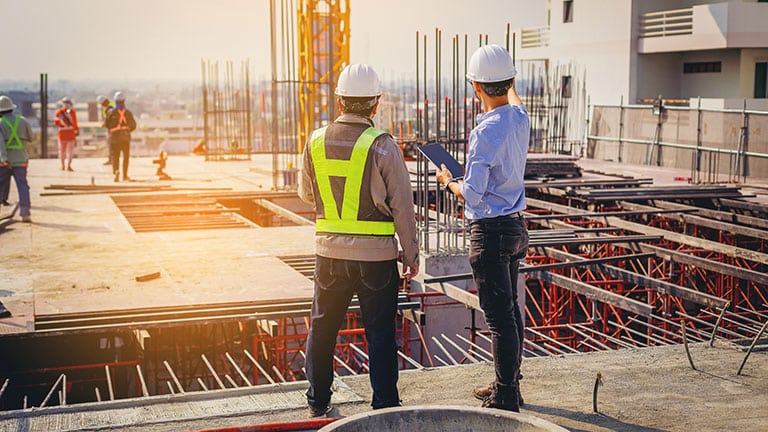 Structural engineer and foreman worker with touch pad discuss, plan working for the outdoors building construction site.