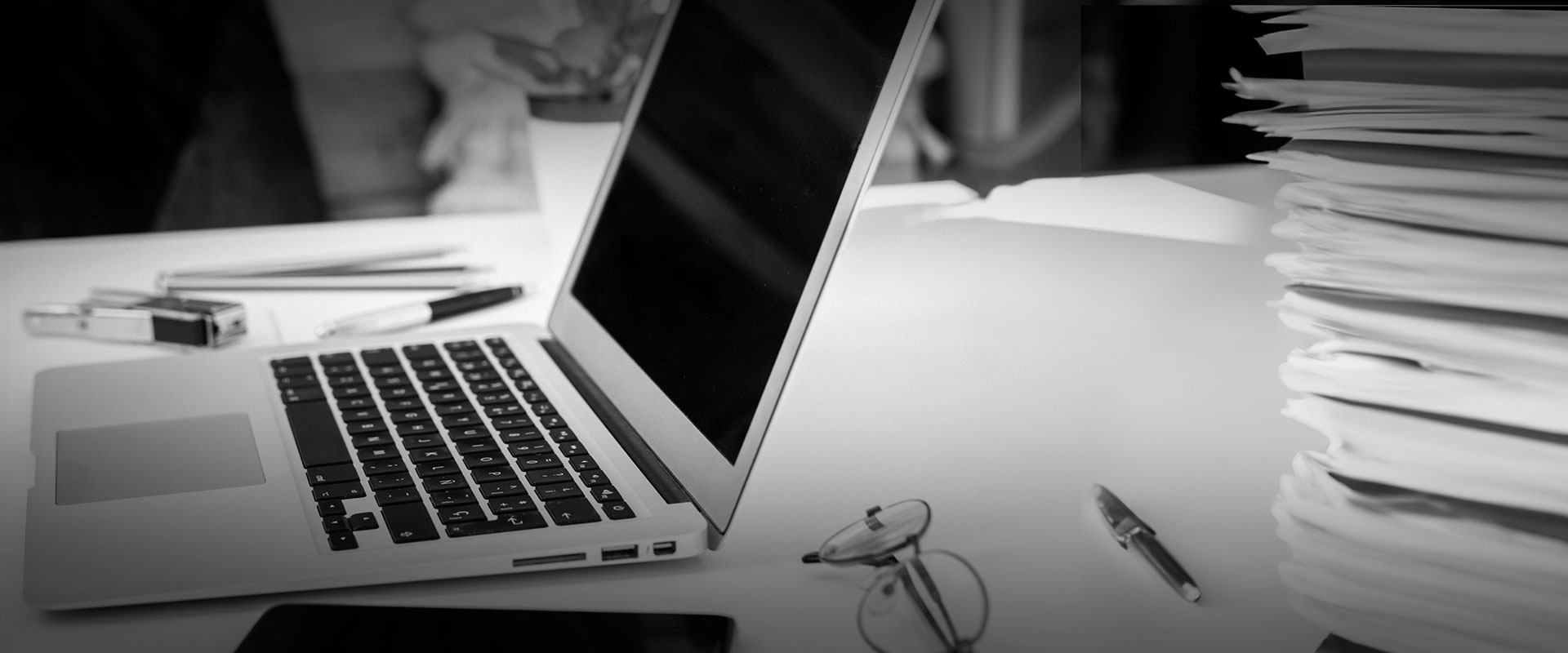 A desk with a laptop computer and a stack of file folders.